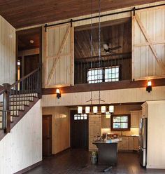 a large open floor plan with wood paneling and metal railings on the second story