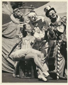 an old black and white photo of clowns posing for the camera with a woman