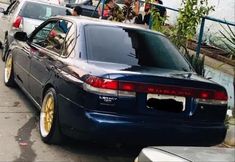 two cars parked on the side of the road with people standing in the back window