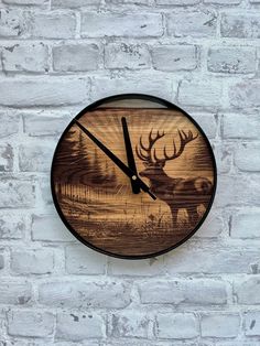 a wooden clock with an image of a deer on it's face is hanging on a brick wall