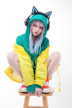 a person sitting on a stool wearing a cat hat and green hoodie with ears