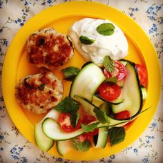 a yellow plate topped with cucumbers, tomatoes and other vegetables next to sour cream