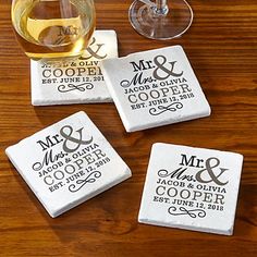 four personalized coasters sitting on top of a wooden table next to a glass of wine