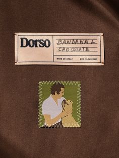 a close up of a label on a jacket with a man holding a small dog