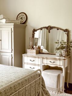 a bedroom scene with focus on the bed and dresser, mirror and clock in the background