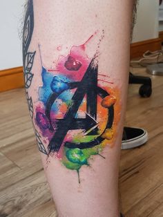 a colorful tattoo on the leg of a man with an avengers symbol painted on it