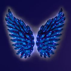 two blue wings with lights on them against a dark background in the shape of an angel