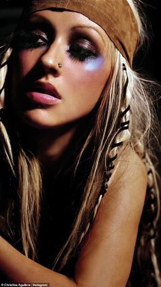 a woman with long blonde hair and blue eyeshade is posing for the camera