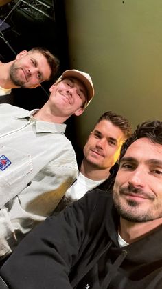 three men sitting next to each other in front of a mirror with one man smiling at the camera