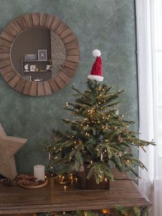 a small christmas tree with a santa hat on top in front of a wall mirror