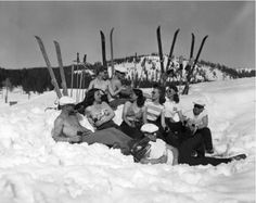 a group of people sitting in the snow next to skis