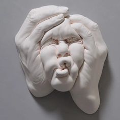 a sculpture of a person's head with hands on it