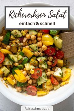 a white bowl filled with chickpeas, zucchini and tomatoes next to a wooden spoon