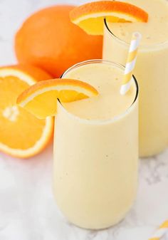 two glasses filled with orange smoothie next to an orange