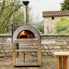 an outdoor pizza oven sitting on top of a brick patio next to a stone wall