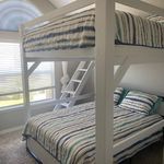 a white bunk bed sitting in a bedroom next to a window with blinds on the windowsill