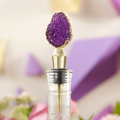 a bottle filled with purple liquid sitting on top of a table next to pink flowers