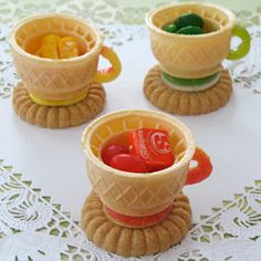 three ice cream cups with gummy bears in them on a doily covered table