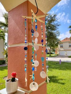 a wind chime hanging on the side of a building with a potted plant next to it