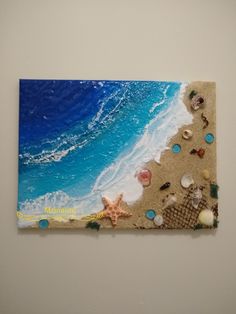 a piece of art with shells and starfish on the beach next to the ocean