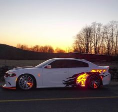 a white car with flames painted on it's side in front of the sun