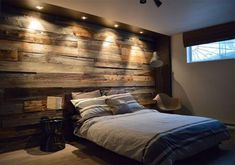 a bedroom with wood paneling and lights on the headboard, along with a bed