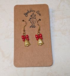 Introducing our elegant Golden Bells Earrings - a breathtaking fusion of sophistication and festive charm. Crafted from polymer clay, these earrings exude the opulent beauty of sparkling gold bells adorned with vibrant red ribbons, creating a statement accessory that embodies the spirit of the season. Each bell is meticulously detailed to capture the richness and shimmer of real gold, ensuring you radiate elegance at every holiday gathering. The festive red ribbons delicately tied on top add a t