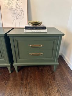 two green nightstands with books on top of them in a living room next to a painting