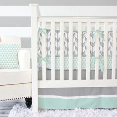 a baby crib with gray and white stripes on the wall next to a chair