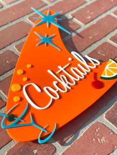 an orange sign with the word cocktails written in white lettering on top of it