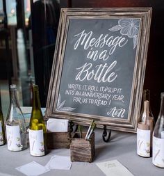 a chalkboard sign sitting on top of a table next to wine glasses and bottles