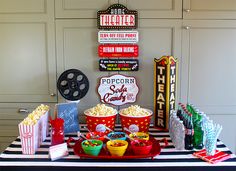 a table topped with popcorn buckets filled with drinks and movie tickets on top of it