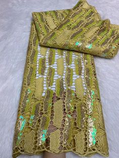 a woman's hand is holding onto a green and gold lace with sequins