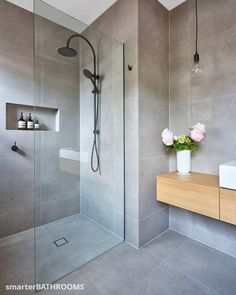 a bathroom with a glass shower door, sink and flowers in the vase on the counter