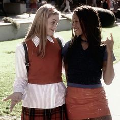 two young women standing next to each other in front of a building and grass area