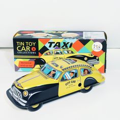 a toy taxi car next to a boxed tin toy card game box on a white surface