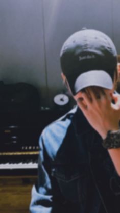 a man sitting in front of a piano talking on a cell phone with his hand to his face