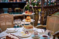 a table topped with plates and cups filled with desserts next to wine glasses on top of a wooden table