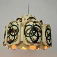 a white and black lamp hanging from a ceiling with lights on it's sides