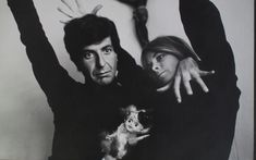 a man and woman are posing with their arms in the air while holding a cat