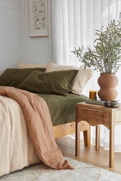 a bed sitting next to a table with a plant on top of it