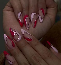 a woman's hands with red and pink nail polishes on their fingertipss