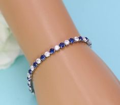 "This exquisitely crafted bracelet boasts 4mm AAA grade cubic zirconia sapphire colored blue and clear round stones in an alternating pattern tennis style bracelet. Bracelet measures 7\", and is perfect for the bride or any special occasion! All jewelry features high quality electroplating that does not fade or chip and is nickel free (hypoallergenic). Orders are shipped via USPS with tracking and confirmation. Item arrives in a complimentary gift box. ------------------------------------------- Sapphire Round Bracelets For Wedding, Sapphire Wedding Bracelets, Elegant Blue Cubic Zirconia Crystal Bracelet, Blue Cubic Zirconia Crystal Bracelet, Sapphire Cubic Zirconia Bracelets, Anniversary Sapphire Diamond Bracelet In Cubic Zirconia, Sapphire Cubic Zirconia Diamond Bracelet For Anniversary, Sapphire Cubic Zirconia Tennis Bracelet, Blue Diamond Wedding Bracelet