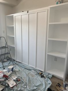 the room is being remodeled with all white paint and shelving units in place on the floor