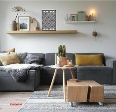 a living room with a gray couch and wooden shelves on the wall above it is a coffee table