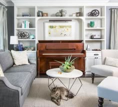 a living room filled with furniture and a cat laying on the floor next to a piano