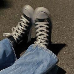 a pair of jeans and sneakers are sitting on the ground with their feet propped up