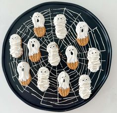 halloween treats with white icing and spooky ghost faces on a black plate