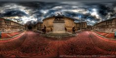 an artistic view of a city square with people walking on the sidewalk and clouds in the sky