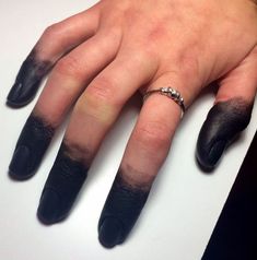 a woman's hand with black nail polish and ring on top of her finger